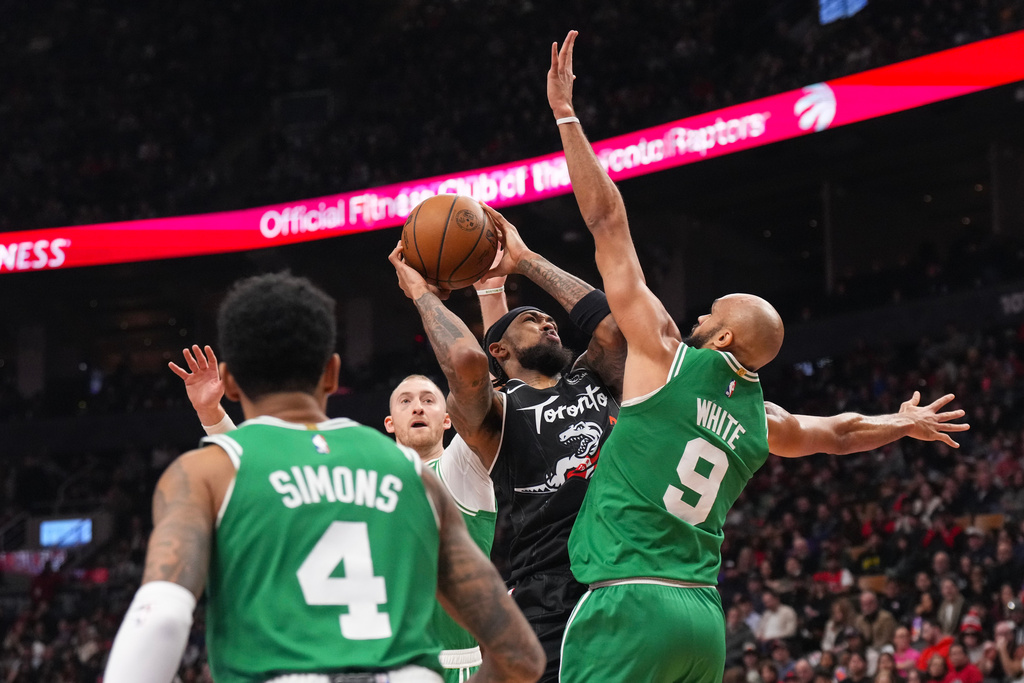 Toronto Raptors forward Brandon Ingram, second from right, looks to shoot against Boston Celtics guard Derrick White (9) during first-half NBA basketball game action in Toronto, Sunday Dec. 7, 2025. (Chris Young/The Canadian Press via AP)