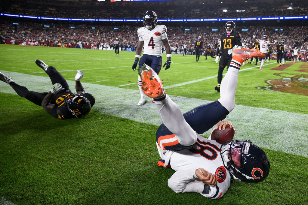 Washington Commanders safety Quan Martin (20) rolls through the play Chicago Bears quarterback Caleb Williams (18) as Williams scores a touchdown during the first half of an NFL football game Monday, Oct. 13, 2025, in Landover, Md. (AP Photo/Nick Wass)