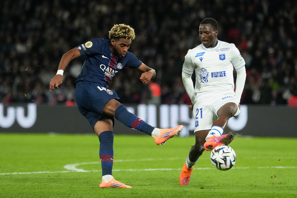 Auxerre's Lasso Coulibaly tries to block a shot from PSG's Ibrahim Mbaye, left, during the French League One soccer match between Paris Saint-Germain and Auxerre at the Parc des Princes in Paris, Saturday, Sept. 27, 2025. (AP Photo/Thibault Camus)