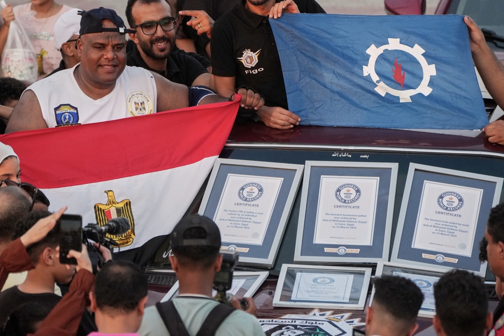 Egyptian wrestler Ashraf Mahrous, also known by his nickname Kabonga, celebrates in front of his Guinness World Records certificates after attempting to pull 20 vehicles at Al Safaa Club in 10th of Ramadan City, outside Cairo, Egypt, Friday, Aug. 1, 2025. (AP Photo/Amr Nabil)