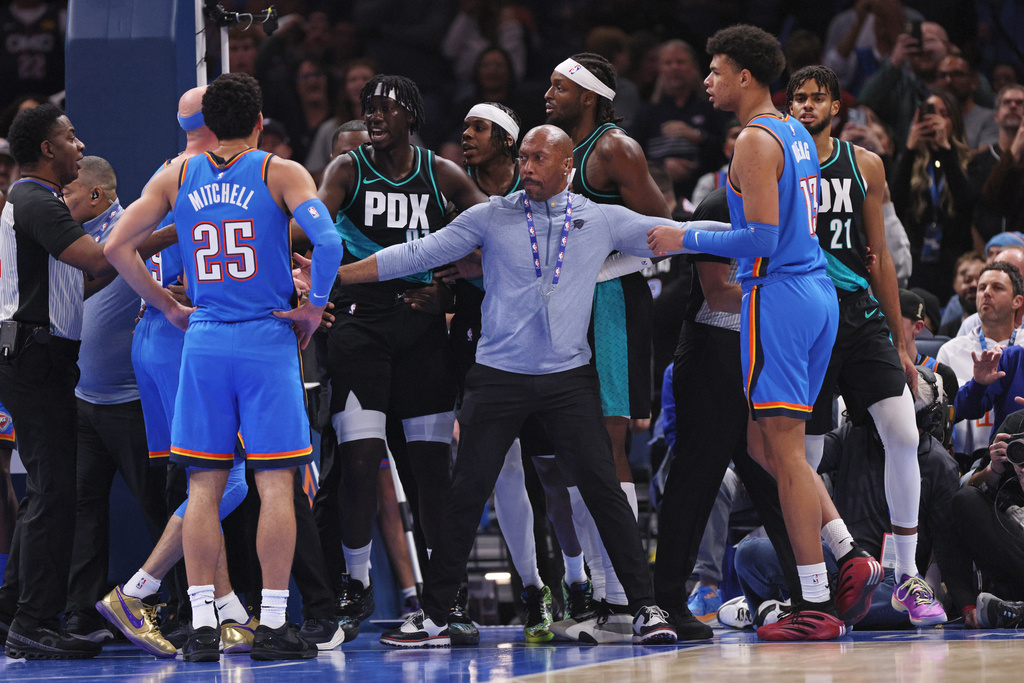 Security separates Oklahoma City Thunder and Portland Trail Blazers players after Trail Blazers guard Rayan Rupert (21) fouled Thunder guard Ajay Mitchell (25) during the first half of an NBA basketball game, Sunday, Nov. 23, 2025, in Oklahoma City. (AP Photo/Nate Billings)