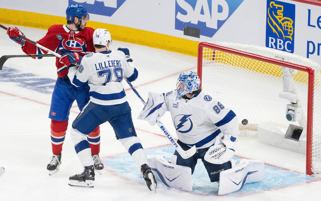 Montreal Canadiens' Kirby Dach, left, and Tampa Bay Lightning's Emil Lilleberg (78) look on as Lightning goaltender Andrei Vasilevskiy (88) is scored against by Canadiens' Lane Hutson during overtime of Game 3 in a first-round NHL hockey Stanley Cup playoff series in Montreal, Friday, April 24, 2026. (Christinne Muschi/The Canadian Press via AP)