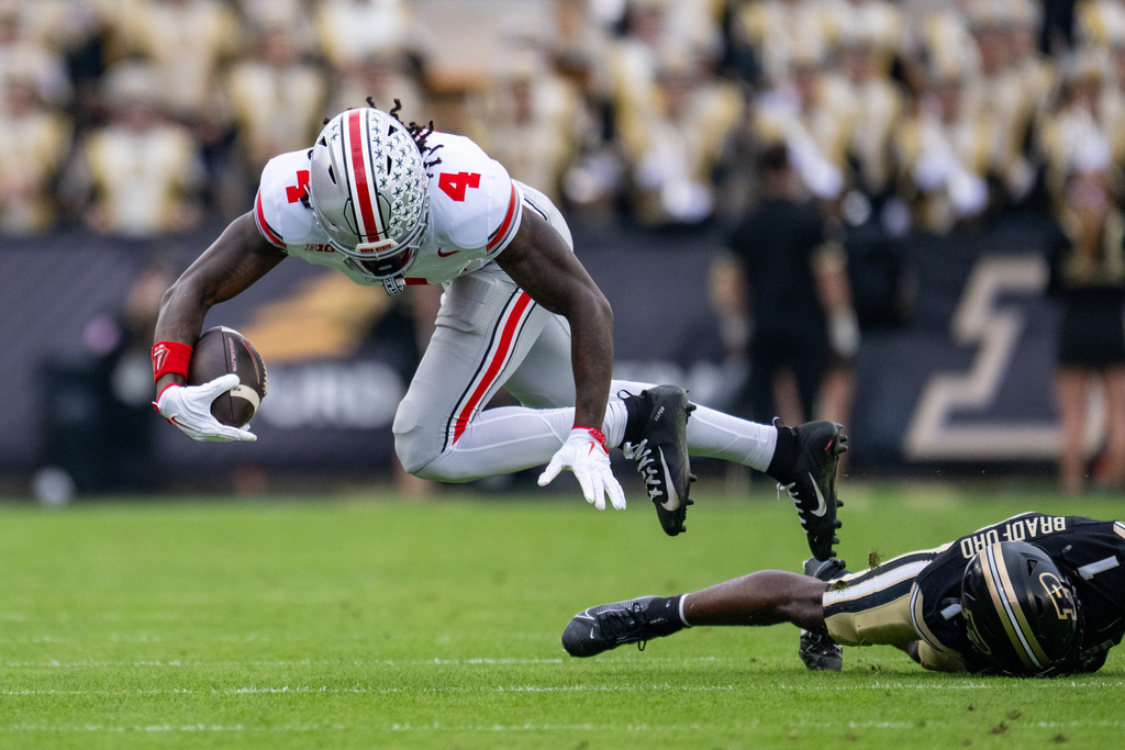 Ohio State wide receiver Jeremiah Smith (4) is tripped up by Purdue defensive back Smiley Bradford (1) during the second half of an NCAA college football game, Saturday, Nov. 8, 2025, in West Lafayette, Ind. (AP Photo/Doug McSchooler)
