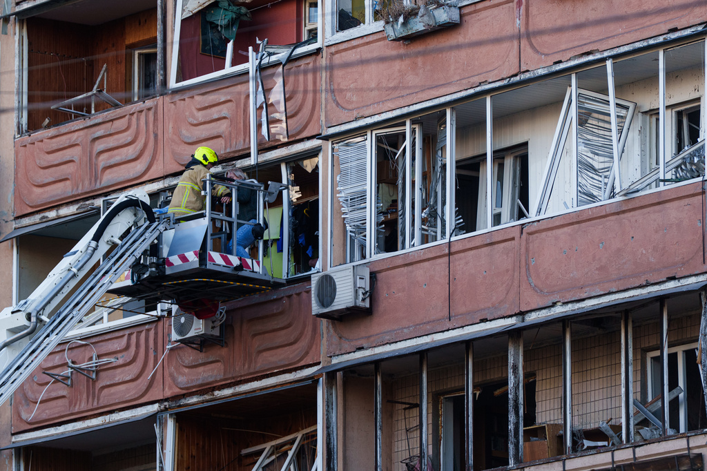 A rescue worker evacuates a woman from a balcony of a house heavily damaged after a Russian strike on residential neighbourhood in Kyiv, Ukraine, on Thursday, May 14, 2026. (AP Photo/Evgeniy Maloletka)