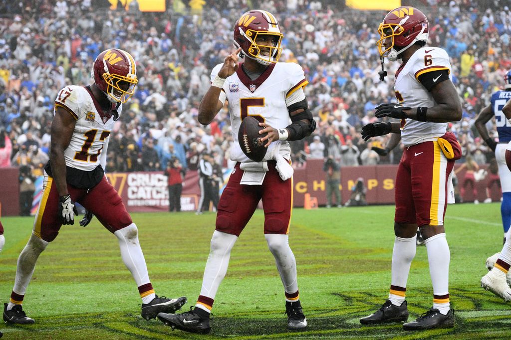 Washington Commanders quarterback Jayden Daniels (5) celebrates with teammates Terry McLaurin (17) and Dyami Brown (6) after scoring a touchdown during the second half of an NFL football game against the New York Giants in Landover, Md., Sunday, Oct. 11, 2026. (AP Photo/Nick Wass)