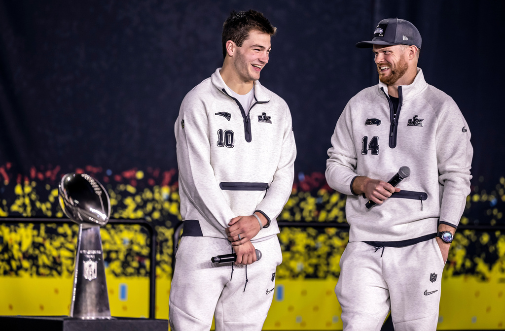 New Englad Patriots quarterback Drake Maye, left, and Seattle Seahawks quarterback Sam Darnold, right, smile on stage with the Lombardi Trophy during the NFL Super Bowl Opening Night, Monday, Feb. 2, 2026, in San Jose, Calif., ahead of the Super Bowl 60 football game between the New England Patriots and the Seattle Seahawks. (Carlos Avila Gonzalez/San Francisco Chronicle via AP)
