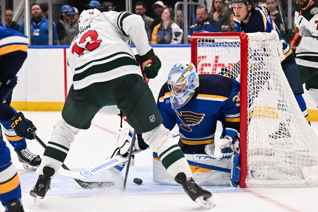 St. Louis Blues' Joel Hofer (30) defends the net against Minnesota Wild's Yakov Trenin (13) during the third period of an NHL hockey game Monday, April 13, 2026, in St. Louis. (AP Photo/Connor Hamilton)