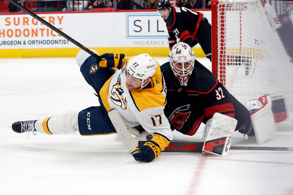 Nashville Predators' Tyson Jost (17) collides with Carolina Hurricanes goaltender Brandon Bussi (32) during the first period of an NHL hockey game in Raleigh, N.C., Saturday, Dec. 6, 2025. (AP Photo/Karl DeBlaker)