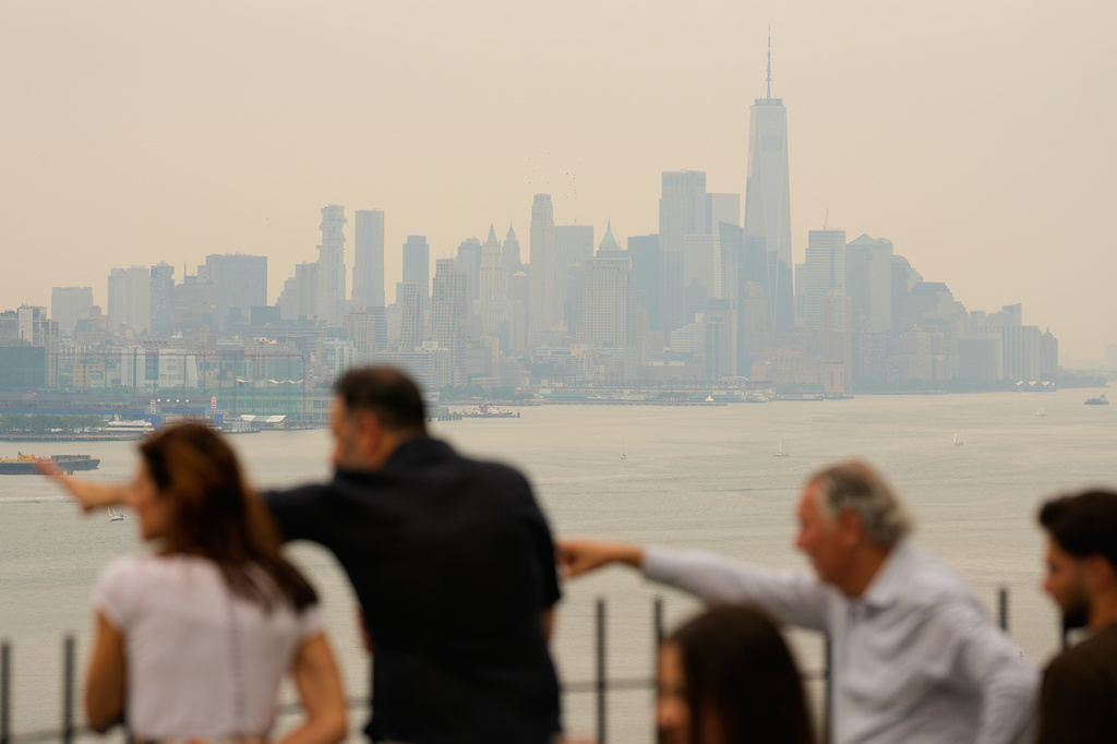 People look over the New York City skyline shrouded in smoke in Weehawken, N.J., Thursday, July 16, 2026. (AP Photo/Seth Wenig)