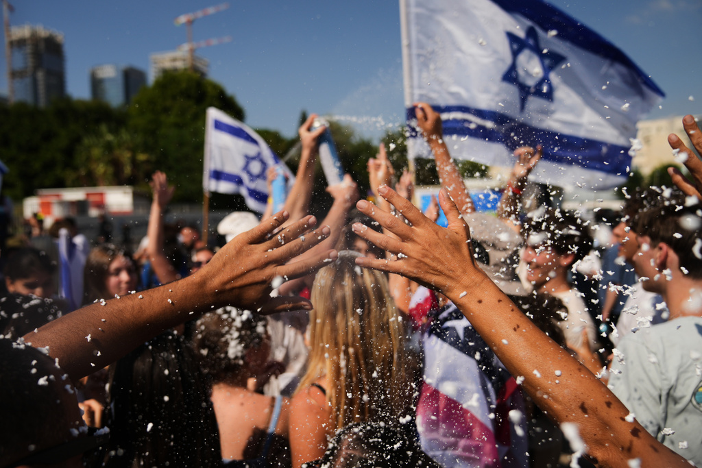 People wave Israeli flags and spray foam in celebration after the arrival of freed hostages at Beilinson Hospital in Petah Tikva, Israel, following their release from Hamas captivity in the Gaza Strip, Monday, Oct. 13, 2025. (AP Photo/Francisco Seco)