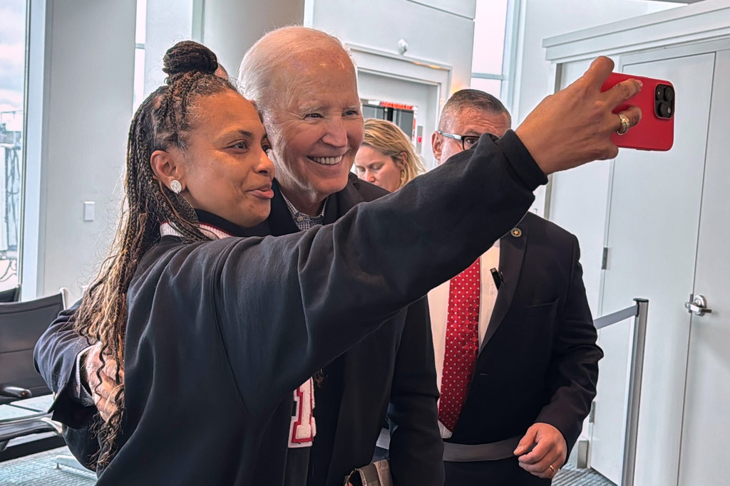 President Joe Biden is greeted by passengers awaiting an outgoing flight and poses for selfies, after his flight arrived, Friday, Feb. 27, 2026 in Columbia, S.C. (AP Photo/Meg Kinnard)
