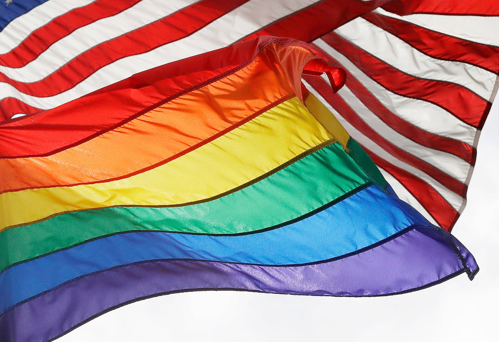 FILE - An LGBTQ+ pride flag flies beneath a U.S. flag at the Stonewall National Monument in New York, on Oct. 11, 2017. (AP Photo/Mark Lennihan, File)