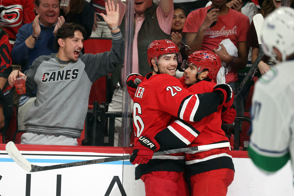 Carolina Hurricanes' Sean Walker (26) congratulates Logan Stankoven, right, on his goal during the second period of an NHL hockey game against the Vancouver Canucks in Raleigh, N.C., Thursday, Oct. 8, 2026. (AP Photo/Karl DeBlaker)