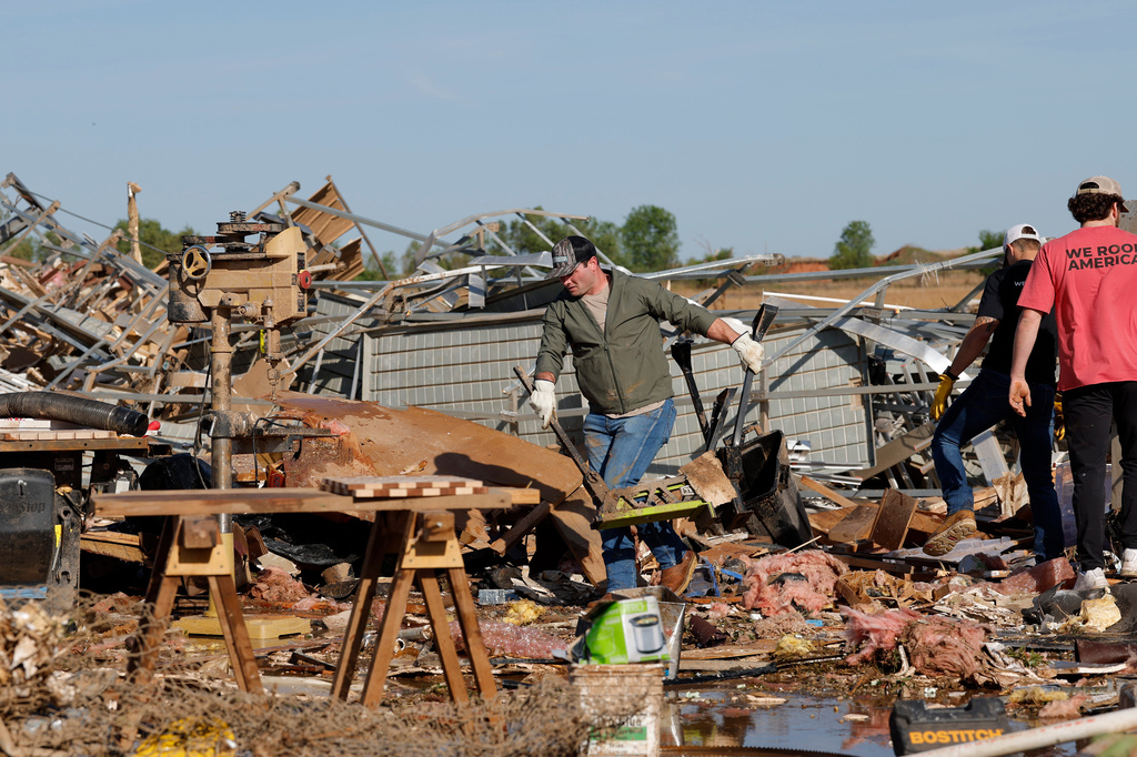 A man clears debris at a commercial woodworking shop in Enid, Okla., Friday, April 24, 2026, in the aftermath of a tornado that barreled through Oklahoma Thursday. (AP Photo/Alonzo Adams)
