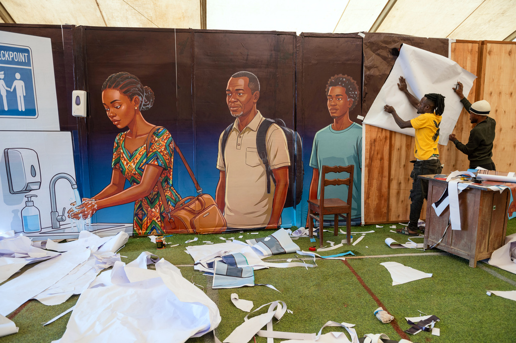 Workers paste a waiting area at Bunia National Airport with Ebola awareness posters in Bunia, Congo, Tuesday, June 2, 2026. (AP Photo/Moses Sawasawa)