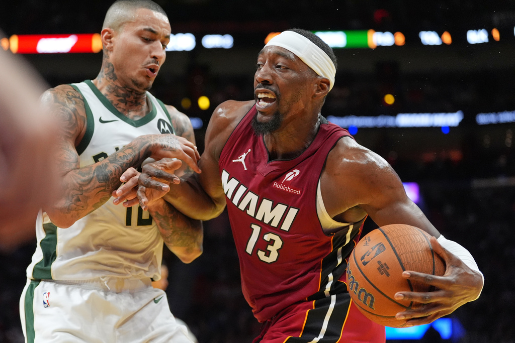 Miami Heat center Bam Adebayo (13) drives past Milwaukee Bucks forward Kyle Kuzma during the first half of an Emirates NBA Cup basketball game, Wednesday, Nov. 26, 2025, in Miami. (AP Photo/Rebecca Blackwell)