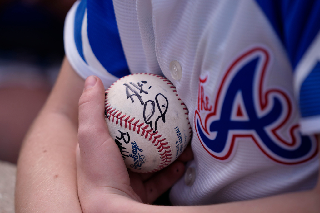 FILE - A young fan holds his baseball as he waits for more autographs from players before a spring training baseball game between the Minnesota Twins and the Atlanta Braves in Fort Myers, Fla., Feb. 22, 2025. (AP Photo/Gerald Herbert, File)