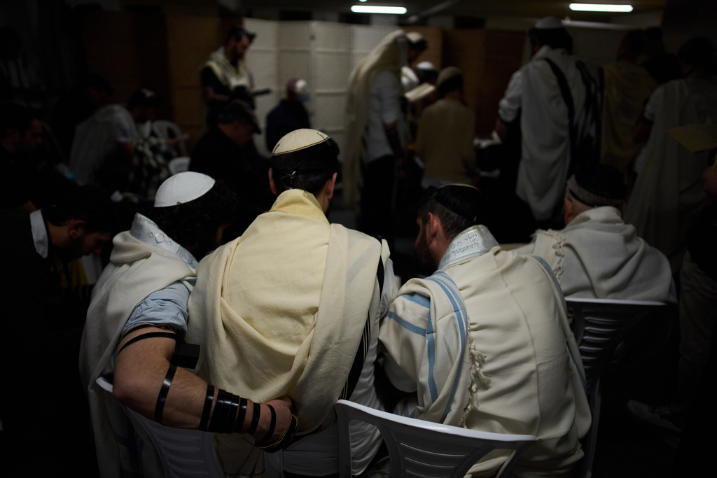 Jewish men covered in prayer shawls pray in an underground parking garage as a precaution against possible Iranian missile attacks, in Tel Aviv, Israel, Tuesday, March 3, 2026. (AP Photo/Oded Balilty)