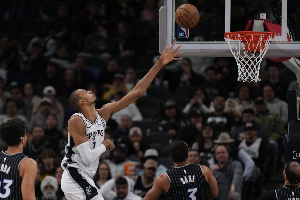 San Antonio Spurs forward Victor Wembanyama (1) scores over Orlando Magic guard Desmond Bane (3) during the first half of an NBA basketball game in San Antonio, Sunday, Feb. 1, 2026. (AP Photo/Eric Gay)