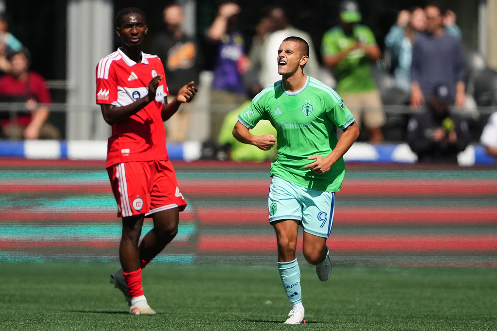 Chicago Fire FC midfielder Dje D'avilla, left, looks on as Seattle Sounders forward Dejan Joveljic celebrates a goal during the first half of an MLS soccer match, Saturday, Aug. 29, 2026, in Seattle. (AP Photo/Lindsey Wasson)