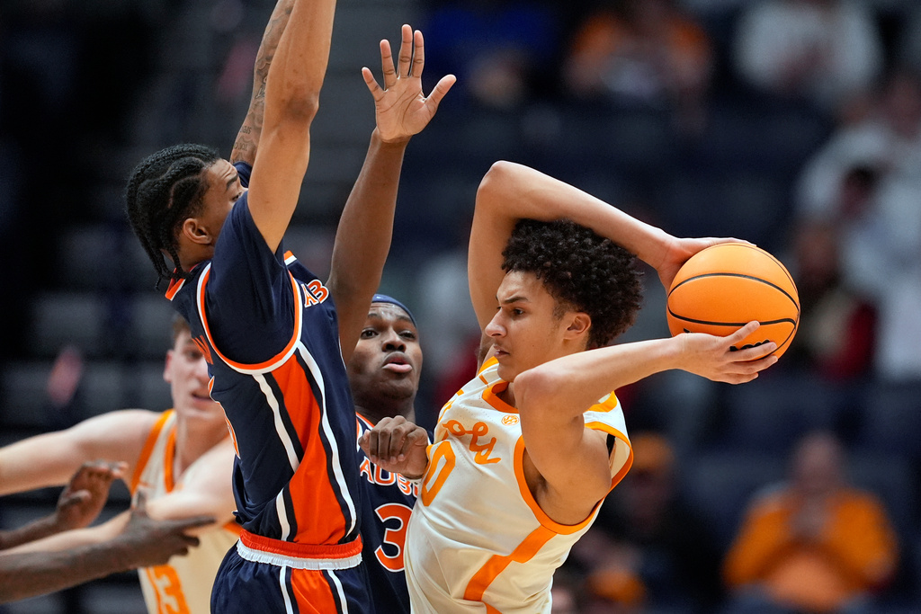Tennessee forward Nate Ament, right, is defended by Auburn guard Elyjah Freeman, left, and forward Sebastian Williams-Adams, middle, during the first half of an NCAA college basketball game in the second round of the Southeastern Conference tournament Thursday, March 12, 2026, in Nashville, Tenn. (AP Photo/George Walker IV)