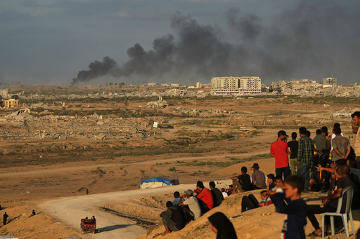 Displaced Palestinians watch smoke rise after Israeli military strikes as they gather on the coastal road near Wadi Gaza, in the central Gaza Strip, Thursday, Oct. 9, 2025. (AP Photo/Abdel Kareem Hana) Displaced Palestinians watch smoke rise after Israeli military strikes as they gather on the coastal road near Wadi Gaza, in the central Gaza Strip, Thursday, Oct. 9, 2025. (AP Photo/Abdel Kareem Hana)