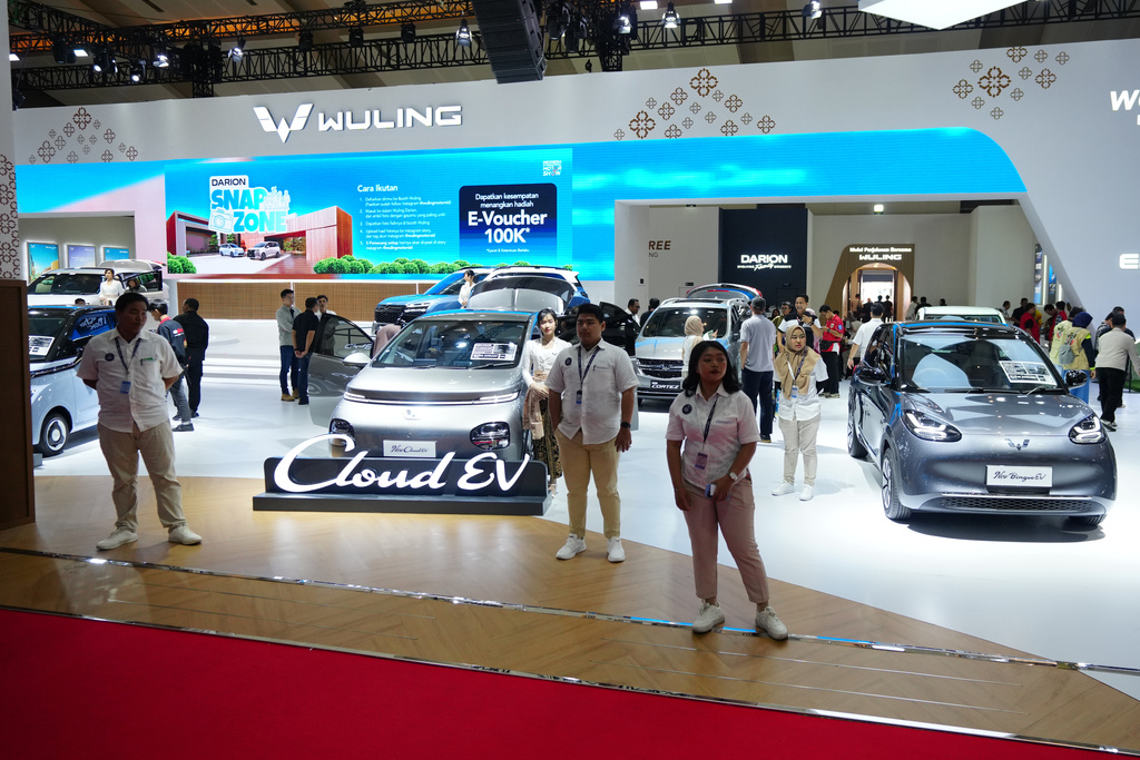 Sales people stand near electric vehicles made by Chinese auto manufacturer Wuling during a motor show in Jakarta, Indonesia Saturday, Feb. 7, 2026. (AP Photo/Tatan Syuflana)