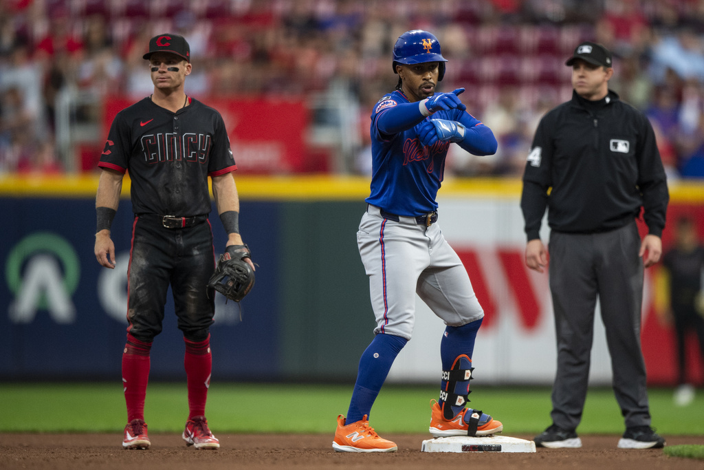 New York Mets Francisco Lindor, center, points at the bench after making it to second base in the third inning of a baseball game against the Cincinnati Reds, Friday, Sept. 5, 2025, in Cincinnati. (AP Photo/Michael Swensen)