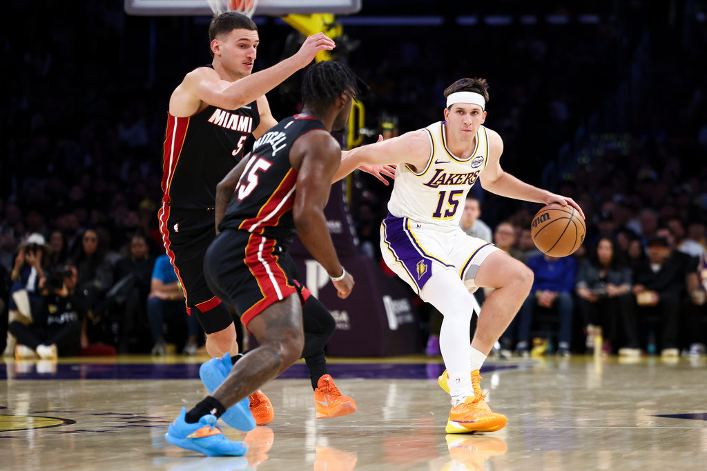 Los Angeles Lakers guard Austin Reaves (15) dribbles against Miami Heat forward Nikola Jovic (5) and guard Davion Mitchell, center, during the first half of an NBA basketball game, Sunday, Nov. 2, 2025, in Los Angeles. (AP Photo/Jessie Alcheh)