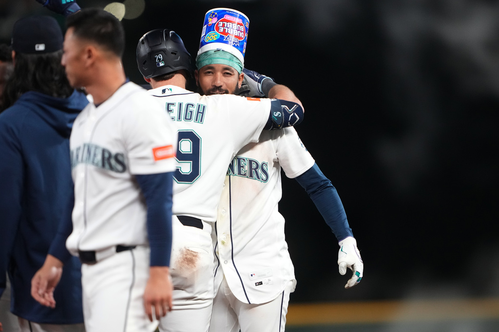 Seattle Mariners' J.P. Crawford, facing, celebrates with Cal Raleigh (29) after hitting a game-winning RBI single against the Houston Astros during the ninth inning of a baseball game, Saturday, April 11, 2026, in Seattle. (AP Photo/Lindsey Wasson)