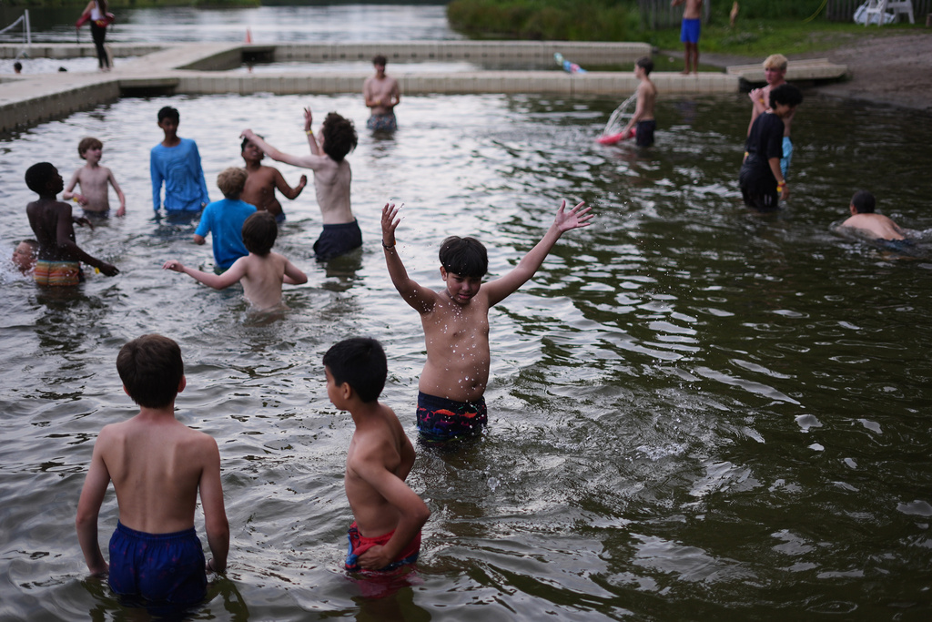 Dylan Aristy Mota, 12, of New York City, center, who has lupus, splashes in the water during an evening swim at the Frost Valley YMCA sleepaway camp in Claryville, N.Y., Wednesday, July 30, 2025. The camp partnered with Children's Hospital at Montefiore so kids with autoimmune diseases could attend for the first time. (AP Photo/Matt Rourke)