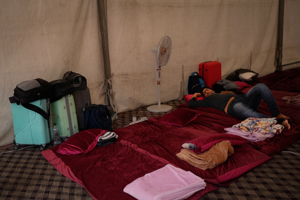 A stranded Indian traveler sleeps inside a tent at a farmhouse owned by an Indian businessman, now converted into a shelter in Ajman, near Dubai, United Arab Emirates, Saturday, March 7, 2026. (AP Photo/Altaf Qadri)