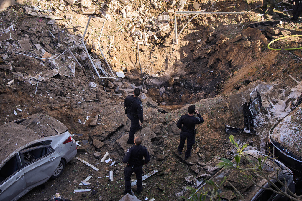 Israeli security forces and rescue teams inspect the site of an Iranian missile strike in Tel Aviv, Israel, Tuesday, March 24, 2026. (AP Photo/Oded Balilty)