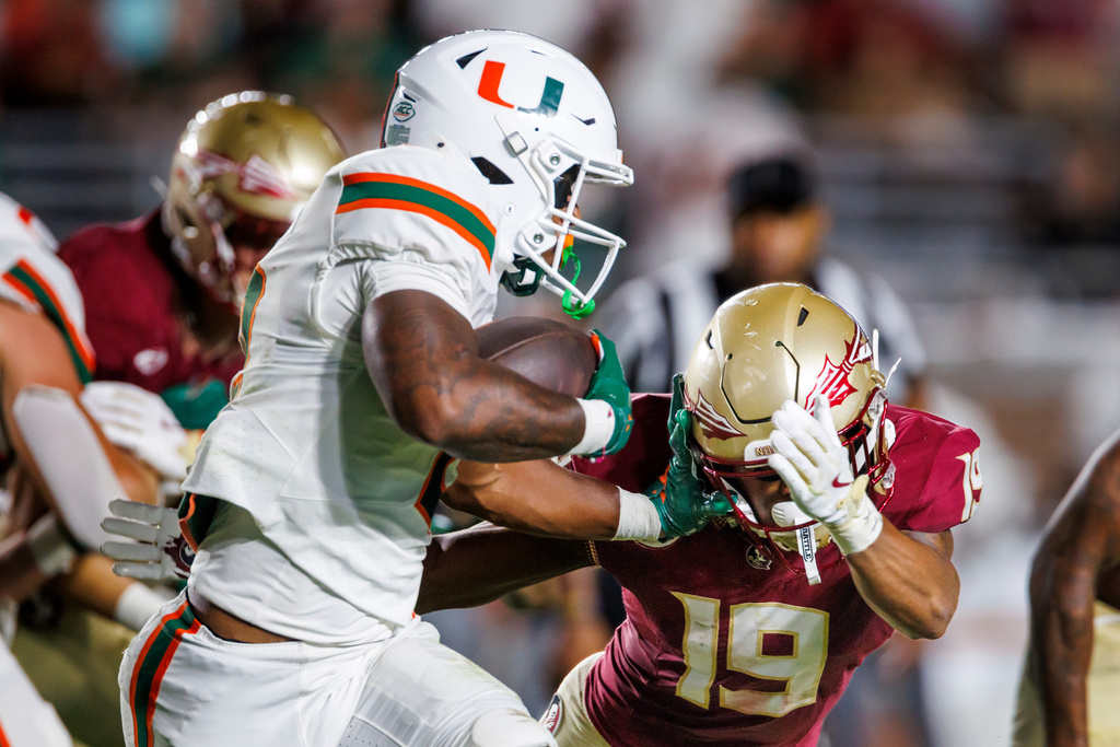 Miami running back Jordan Lyle (2) pushes away Florida State defensive back Jerry Wilson (19) during the second half of an NCAA college football game, Saturday, Oct. 4, 2025, in Tallahassee, Fla. (AP Photo/Colin Hackley)