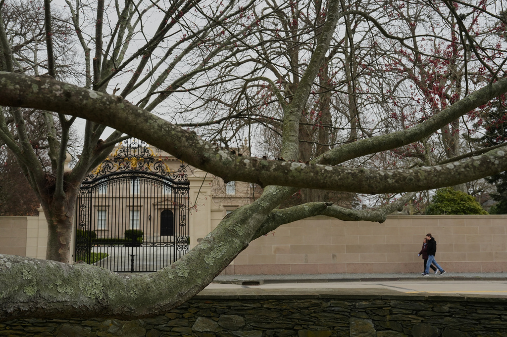 People walk near a mansion and a red maple tree Wednesday, April 22, 2026, in Newport, R.I. (AP Photo/Joshua A. Bickel)