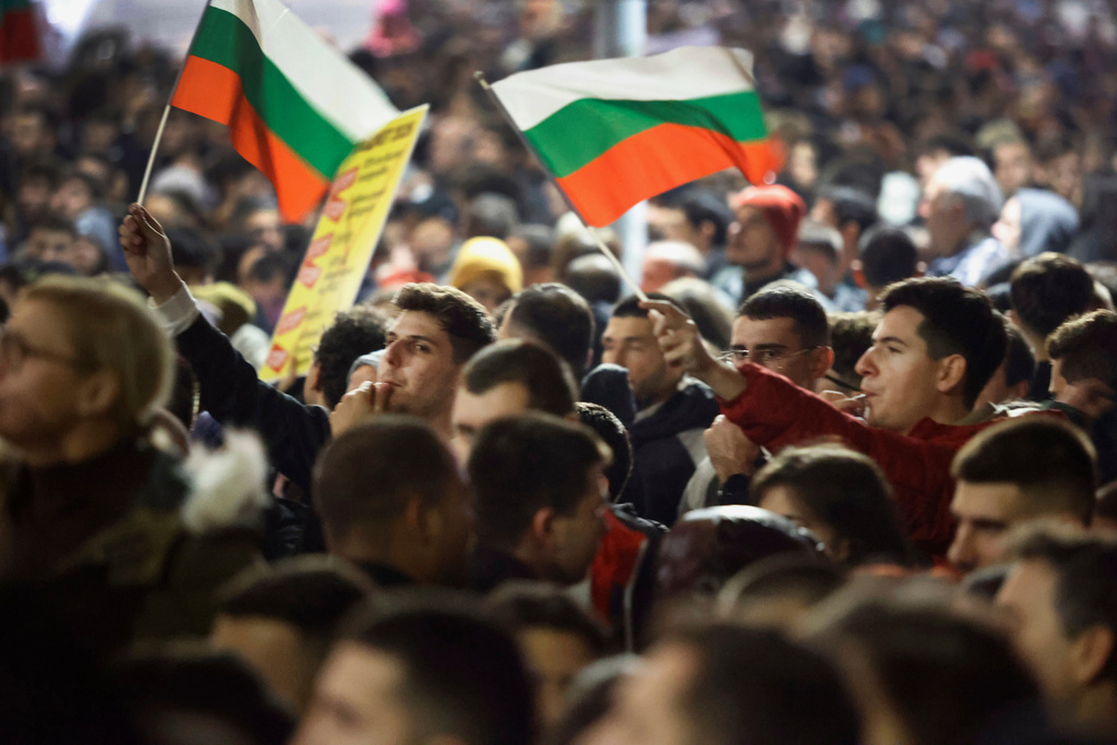 Protesters whistle and wave Bulgarian flags as thousands took to the streets of Bulgaria's capital, Sofia, to denounce steep tax hikes in next year's draft budget before being finally voted on in parliament, Wednesday, Nov 26, 2025. (AP Photo/Valentina Petrova)