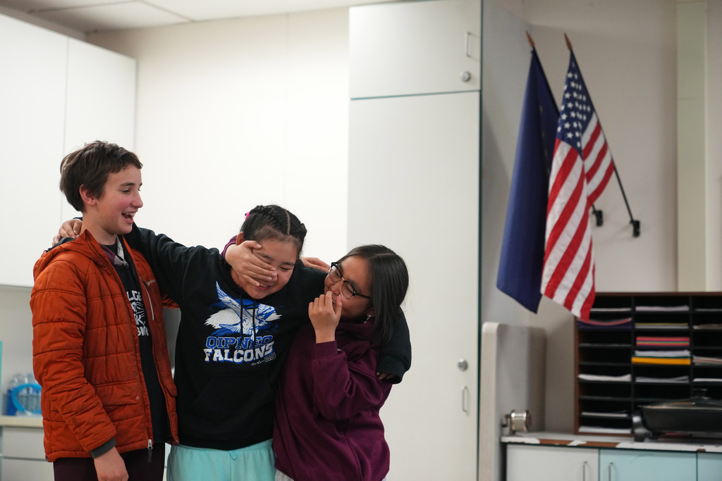 From left, Lilly Loewen, 10, a student from Anchorage, jokes around with new classmates Rayann Martin, center and Ellyne Aliralria, right, both 10-year-olds displaced from Kipnuk, at College Gate Elementary, where students spend half their time learning in Yup'ik language immersion, Thursday, Oct. 30, 2025, in Anchorage, Alaska. (AP Photo/Lindsey Wasson)