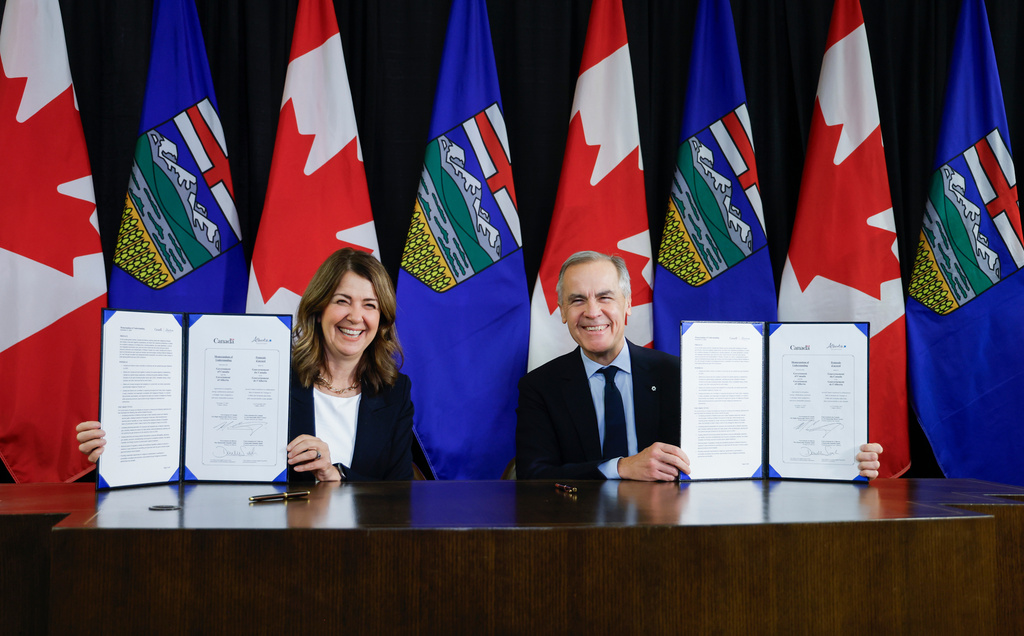 Prime Minister Mark Carney, right, signs an MOU with Alberta Premier Danielle Smith in Calgary, Alta., Thursday, Nov. 27, 2025. (Jeff McIntosh /The Canadian Press via AP)