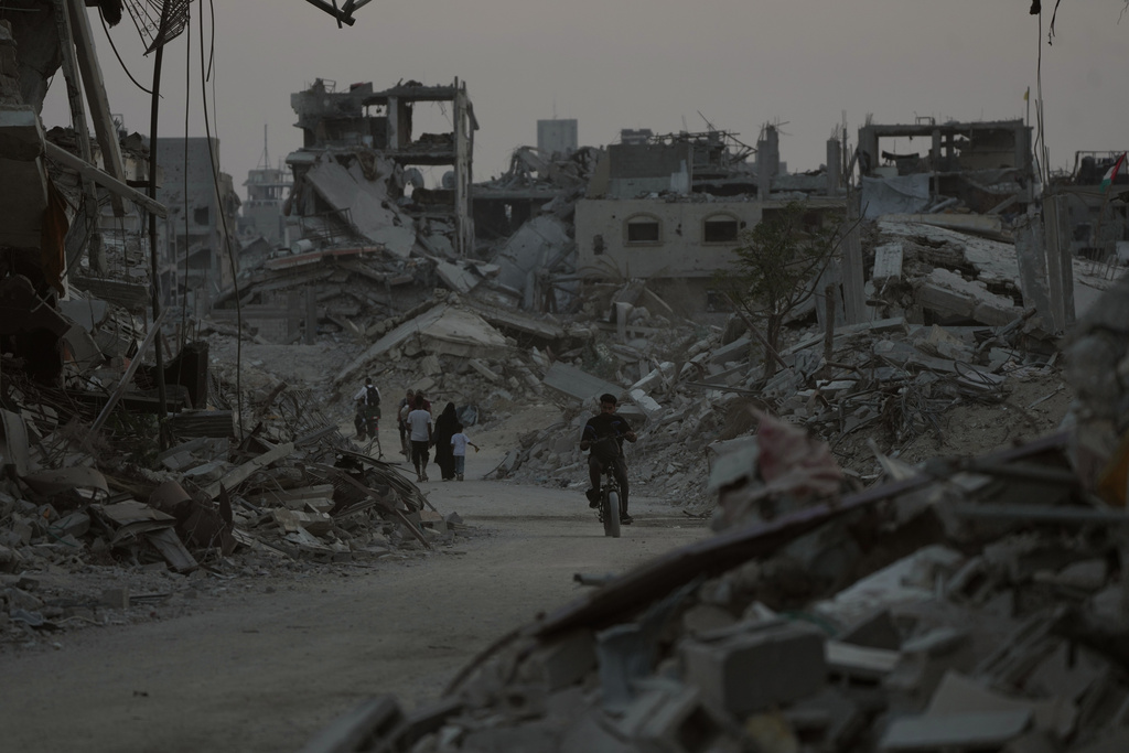 Displaced Palestinians walk among the ruins of destroyed buildings in Khan Younis, Gaza Strip, Saturday, Nov. 8, 2025. (AP Photo/Abdel Kareem Hana)