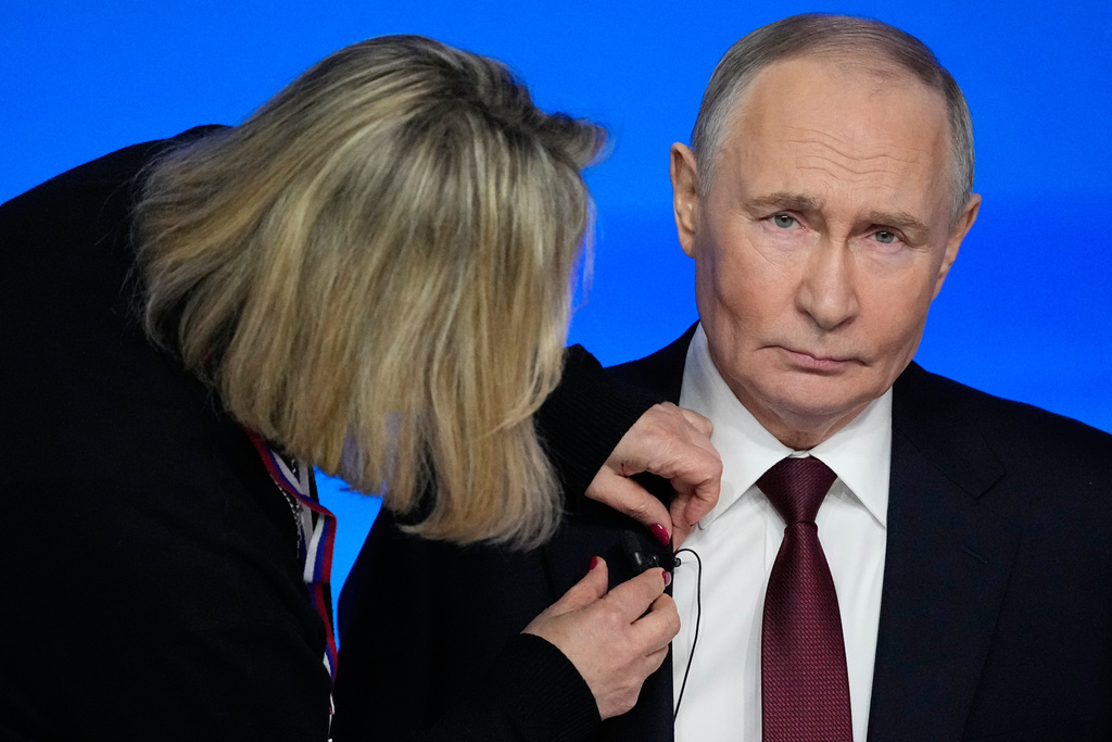 A TV assistant attaches a microphone to Russian President Vladimir Putin's suit prior to his annual news conference and call-in show at Gostinny Dvor, in Moscow, on Friday, Dec. 19, 2025. (AP Photo/Pavel Bednyakov)