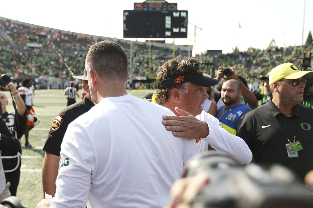 Oregon head coach Dan Lanning, left, greets Oklahoma State head coach Mike Gundy, center right, after an NCAA college football game, Saturday, Sept. 6, 2025, in Eugene, Ore. (AP Photo/Lydia Ely)
