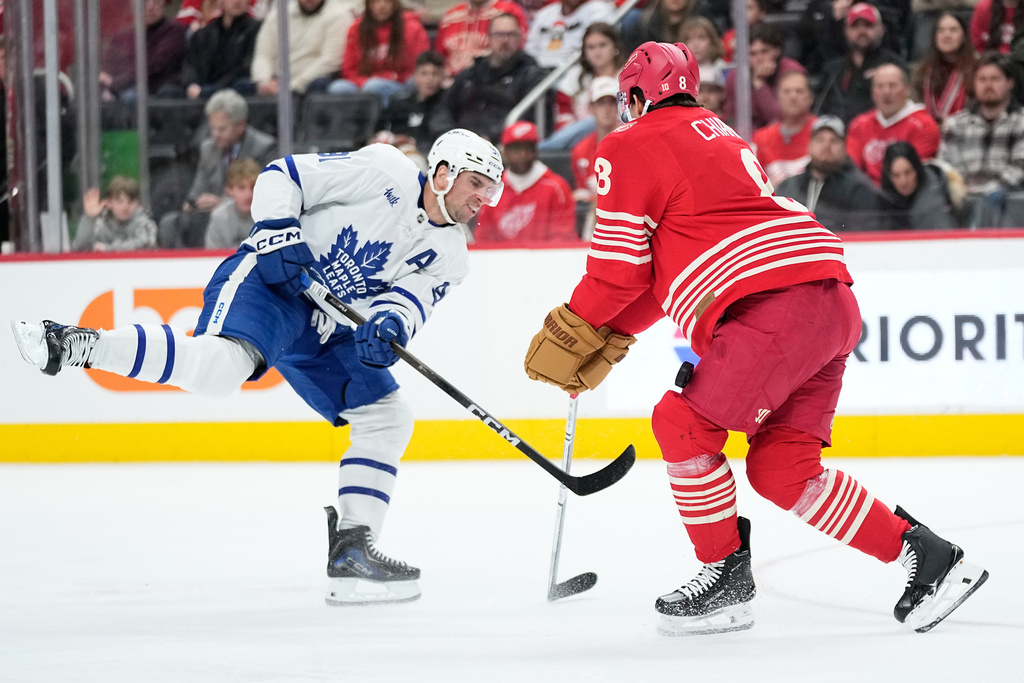 Toronto Maple Leafs center Dakota Joshua, left, shoots against Detroit Red Wings defenseman Ben Chiarot, right, during the first period of an NHL hockey game Sunday, Dec. 28, 2025, in Detroit. (AP Photo/Ryan Sun)