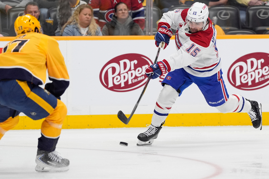 Montreal Canadiens center Alex Newhook (15) shoots the puck past Nashville Predators center Tyson Jost (17) during the first period of an NHL hockey game Saturday, March 28, 2026, in Nashville, Tenn. (AP Photo/George Walker IV)