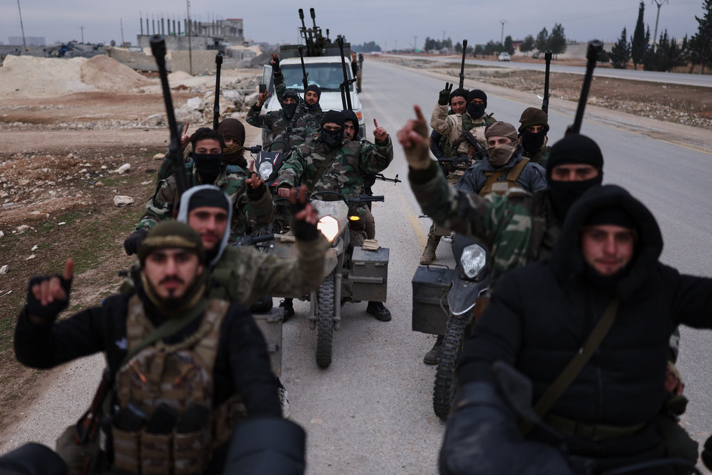 FILE - Syrian government soldiers carry machine guns as they ride motorcycles on a road leading to the town of Deir Hafer, Syria, Saturday, Jan. 17, 2026. (AP Photo/Ghaith Alsayed)