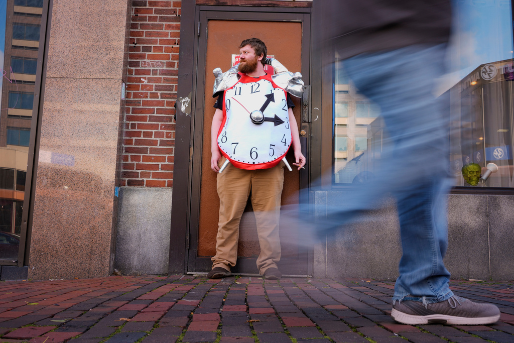 Pharmacy manager Tyler O'Neil wears an alarm clock costume while taking a work break, Friday, Oct. 31, 2025, in Portland, Maine. (AP Photo/Robert F. Bukaty)