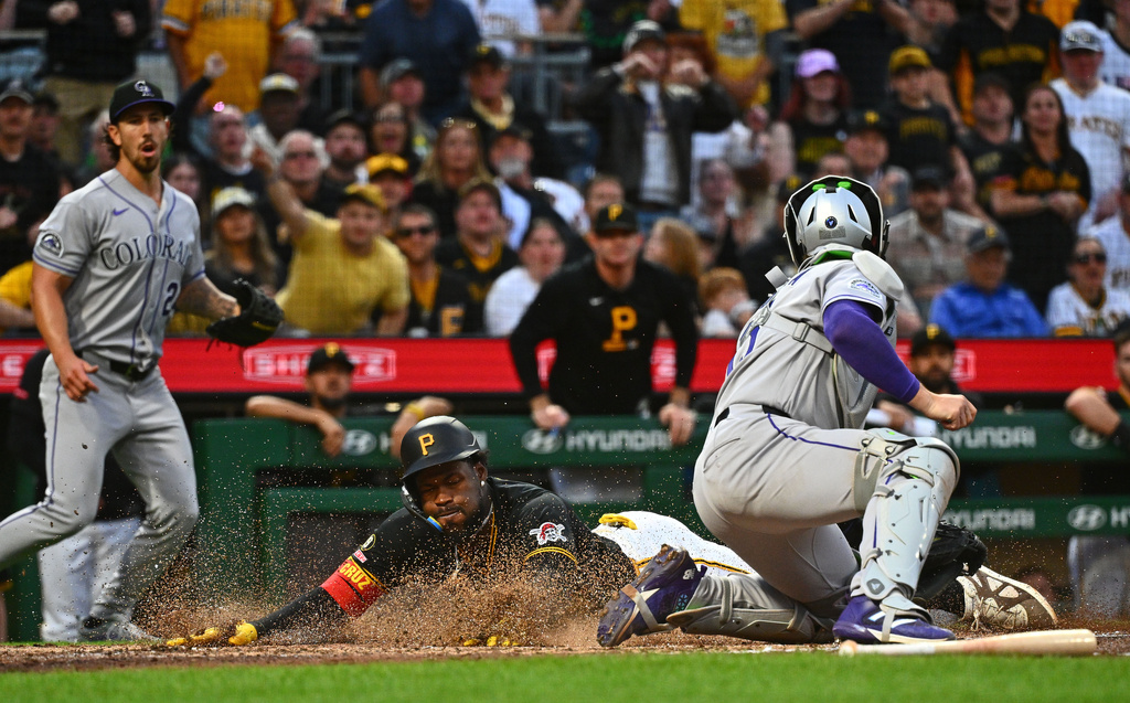 Pittsburgh Pirates' Oneil Cruz, left, slides safely under the tag by Colorado Rockies catcher Hunter Goodman to score on a single by Brandon Lowe during the fifth inning of a baseball game in Pittsburgh, Tuesday, May 12, 2026. (AP Photo/Justin Berl)