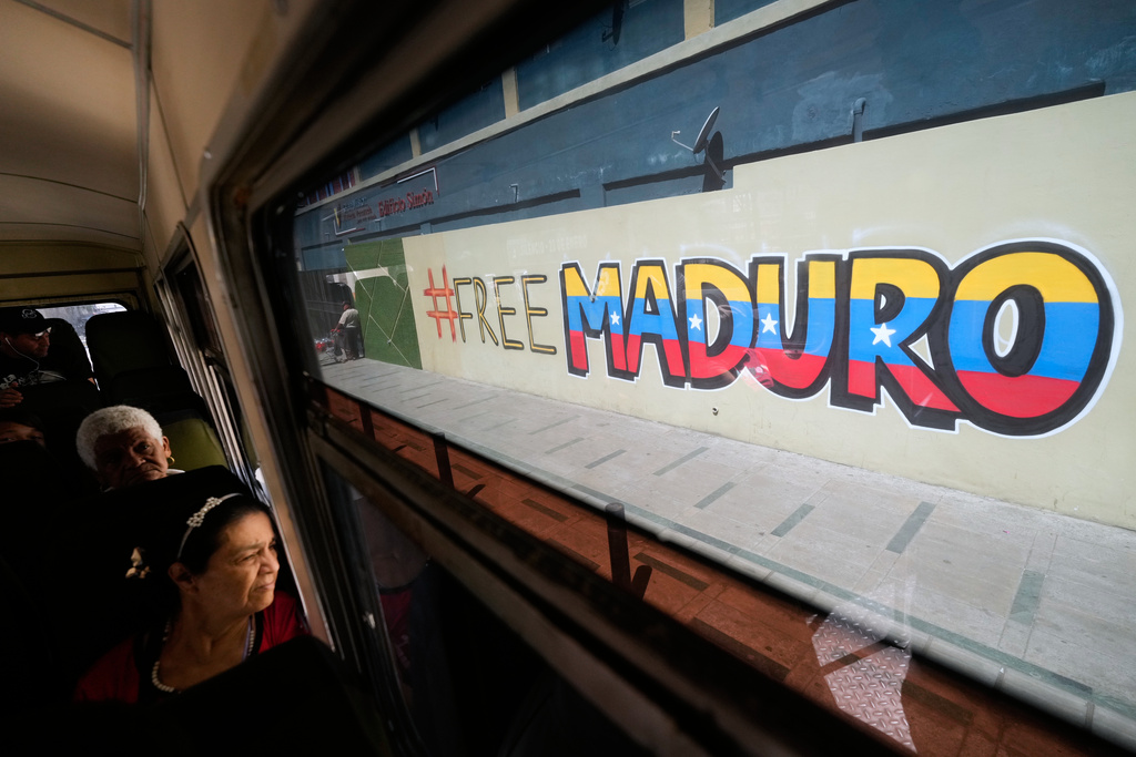 Commuters ride a bus past a mural calling for the release of former Venezuelan President Nicolas Maduro, who was detained by U.S. forces, in Caracas, Venezuela, Thursday, Jan. 8, 2026. (AP Photo/Matias Delacroix)