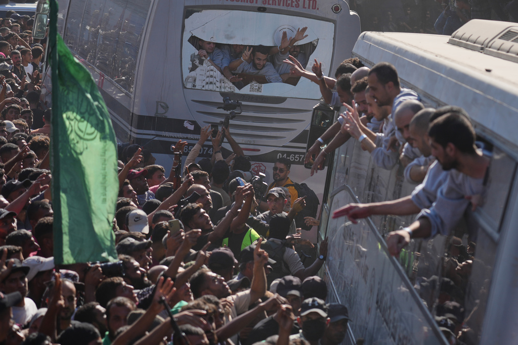 People gather to greet freed Palestinian prisoners arriving on buses in the Gaza Strip after their release from Israeli jails under a ceasefire agreement between Hamas and Israel, outside Nasser Hospital in Khan Younis, southern Gaza Strip, Monday, Oct. 13, 2025. (AP Photo/Jehad Alshrafi)