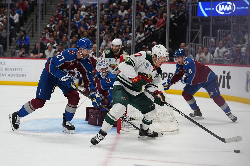 Minnesota Wild left wing Kirill Kaprizov, front right, collects the puck as Colorado Avalanche defensemen Brett Kulak, front left, and Cale Makar, back, cover in the second period of Game 1 of an NHL hockey Stanley Cup second-round playoff series Sunday, May 3, 2026, in Denver. (AP Photo/David Zalubowski)