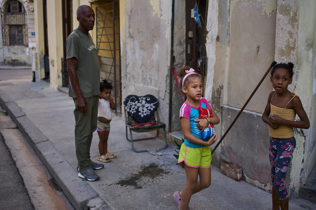 Cristobal Estrada, left, sends his daughter Edianet, center, with a bag of rice to their home in Havana, Cuba, Wednesday, March 25, 2026. (AP Photo/Ramon Espinosa)